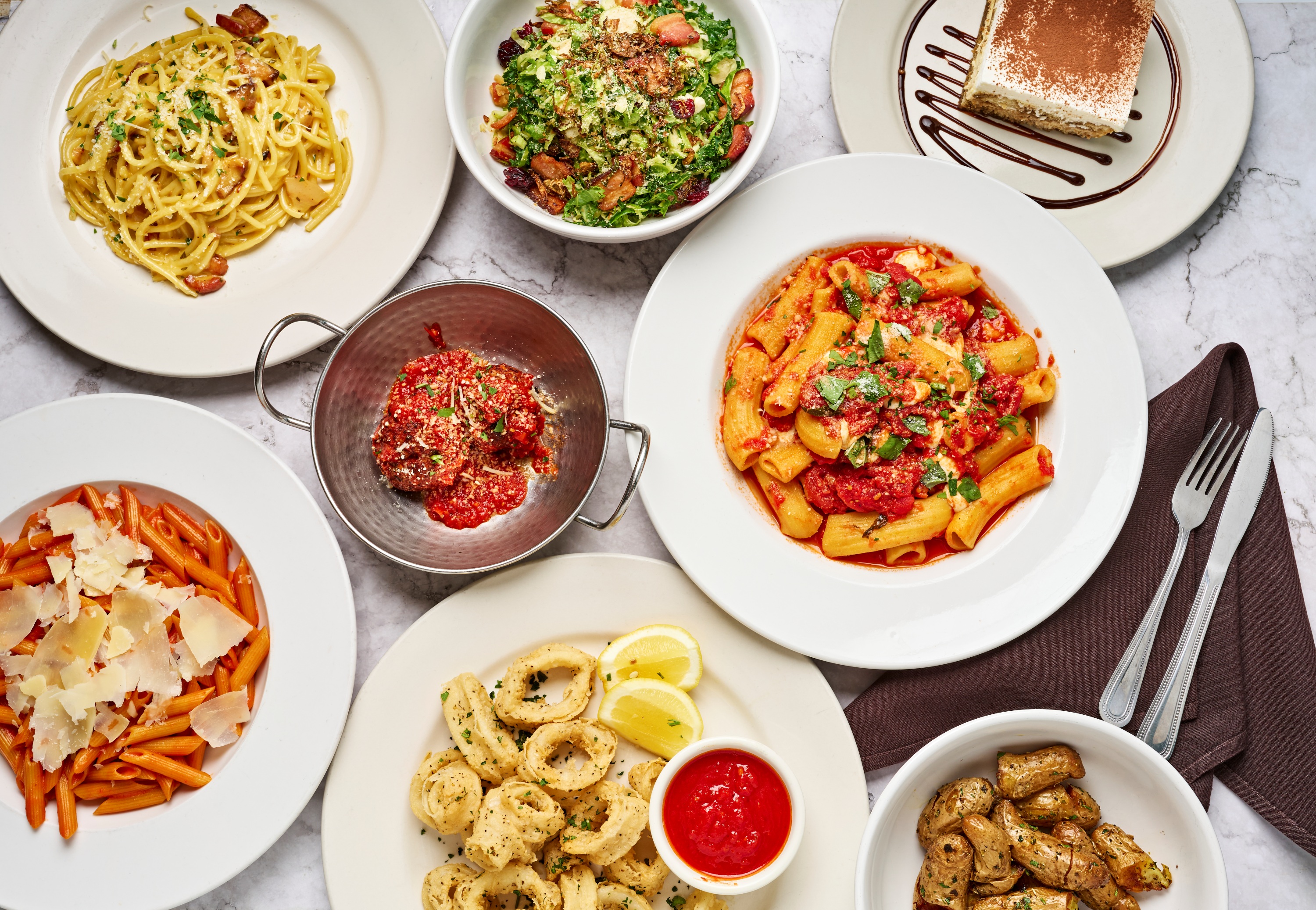 Plates of spaghetti, penne and gnocchi on a wooden table at Sapori